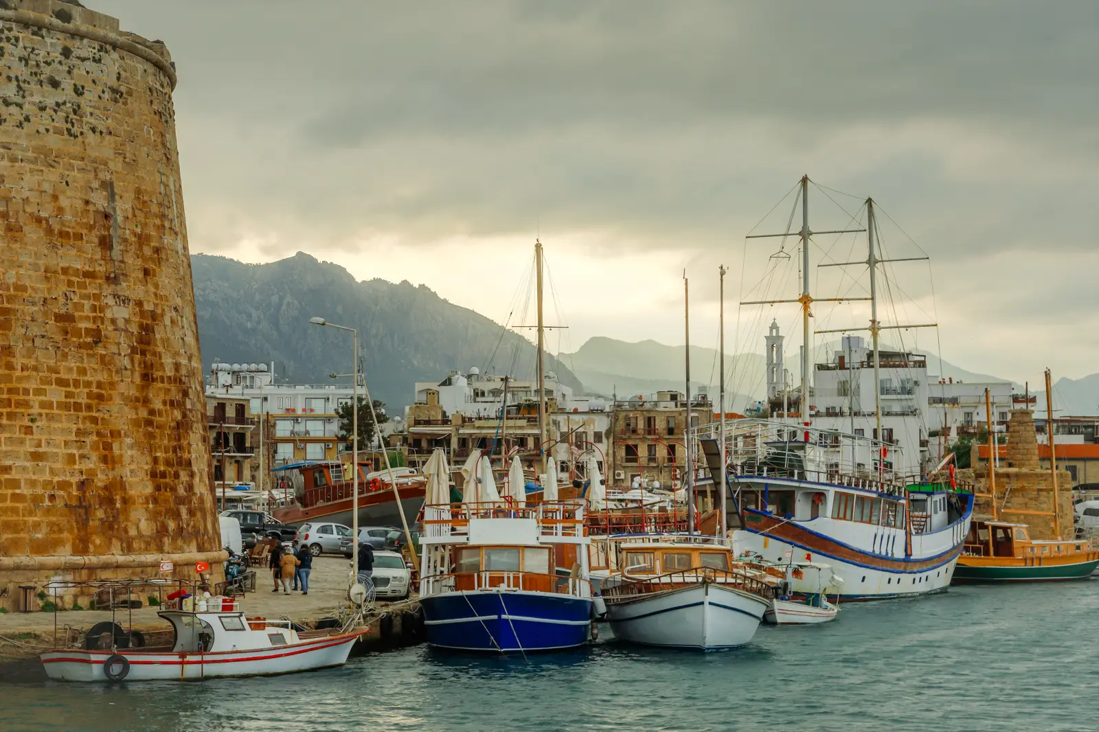 Girne tarihi limanında bağlı ahşap guletler ve arkada dağlar
